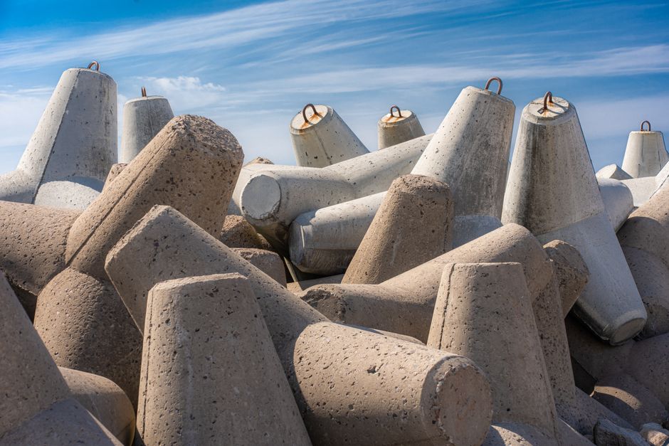 Concrete wave breakers piled on Ventspils shore under a sunny blue sky.