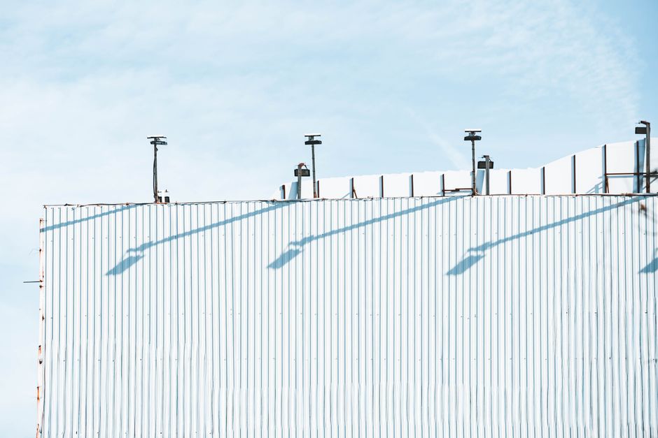 A minimalist industrial structure against a bright blue sky, featuring clean geometric lines.