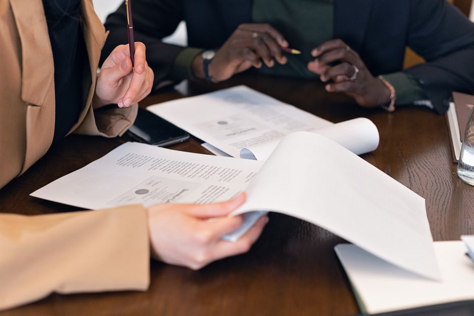 Close-up of professionals reviewing documents during a business meeting in an office setting.