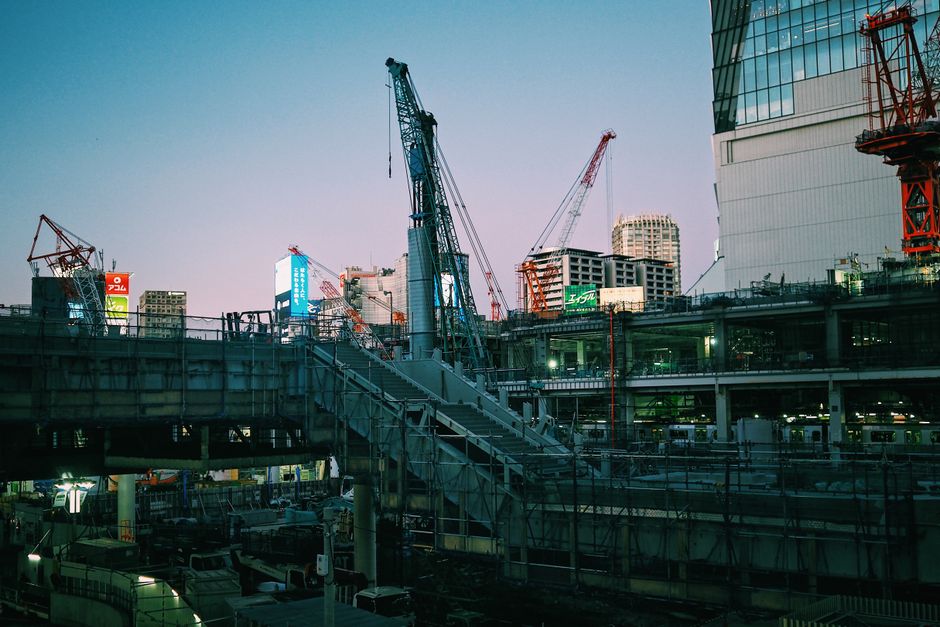 A bustling construction scene in Tokyo, Japan featuring cranes and buildings at dusk.