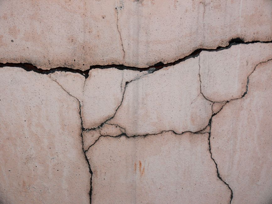 Close-up of a cracked concrete wall, showcasing its unique texture and patterns.