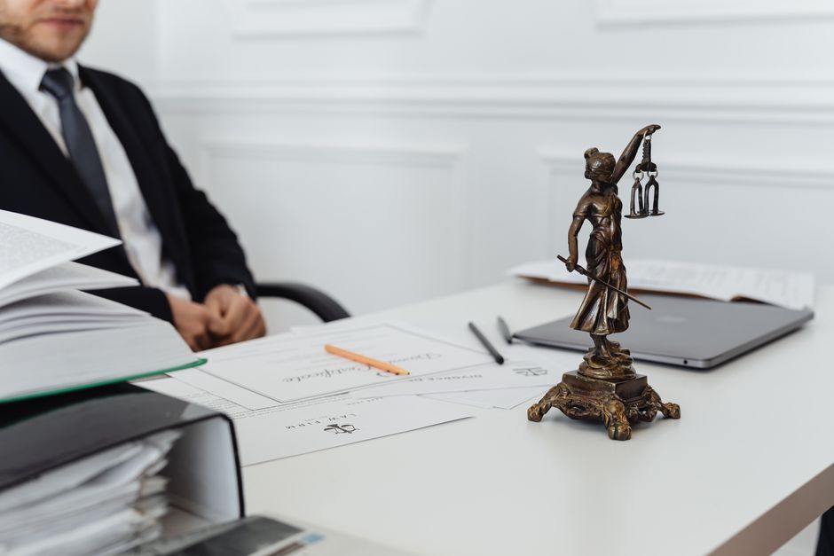 A legal professional’s workspace featuring Lady Justice statue, documents, and a laptop.