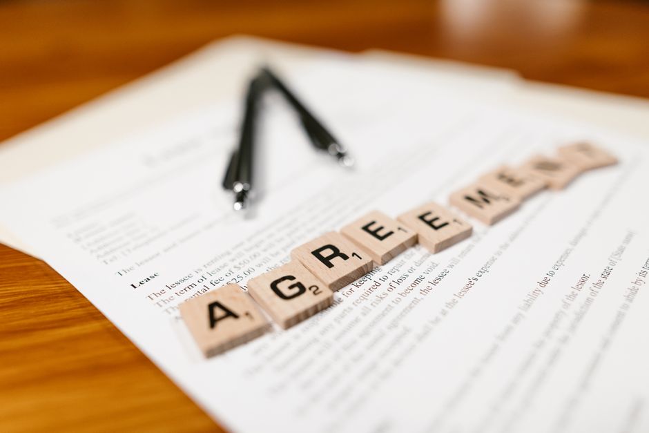 Scrabble tiles spelling ’AGREEMENT’ on a lease document, emphasizing contractual themes.