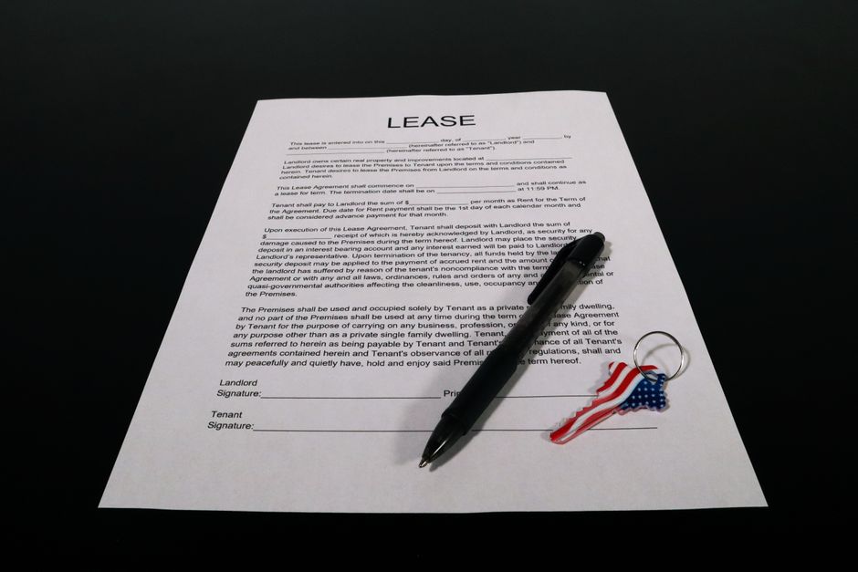 Lease agreement document with pen and American flag keychain on a black table.